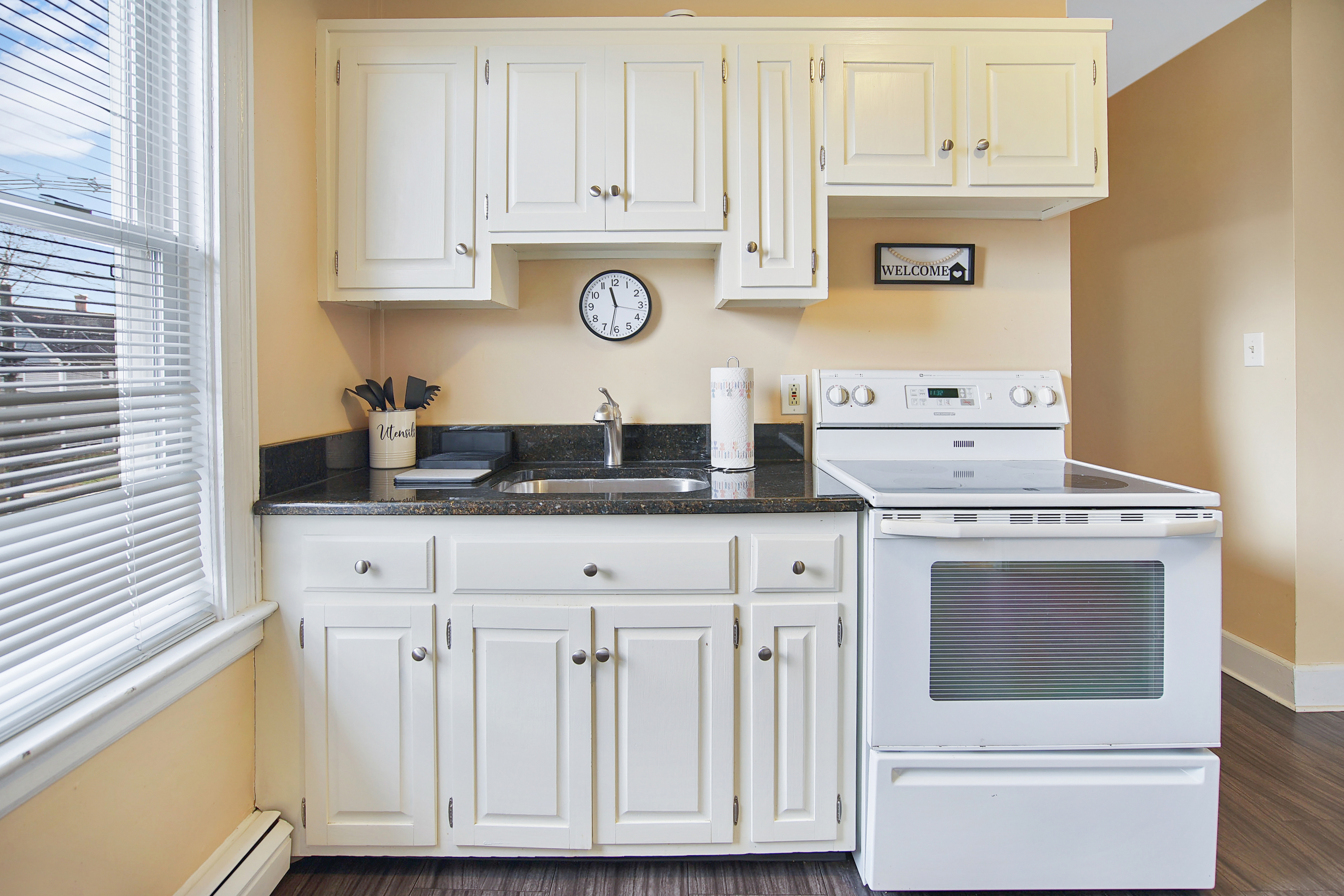 Full kitchen with white cabinetry and granite counters